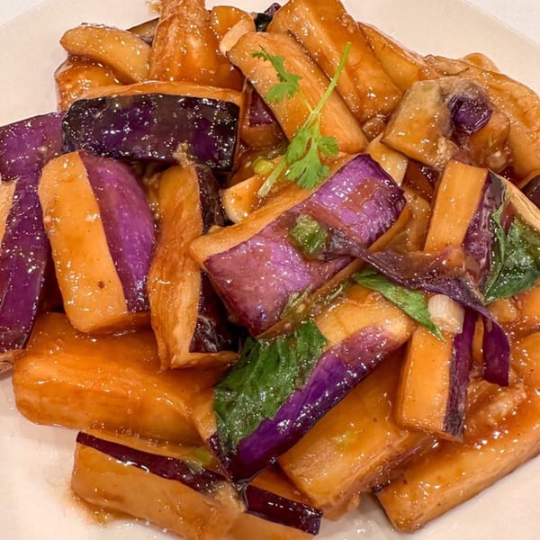 Close-up of Taiwanese stir-fried eggplant with a glossy brown sauce and green herbs.